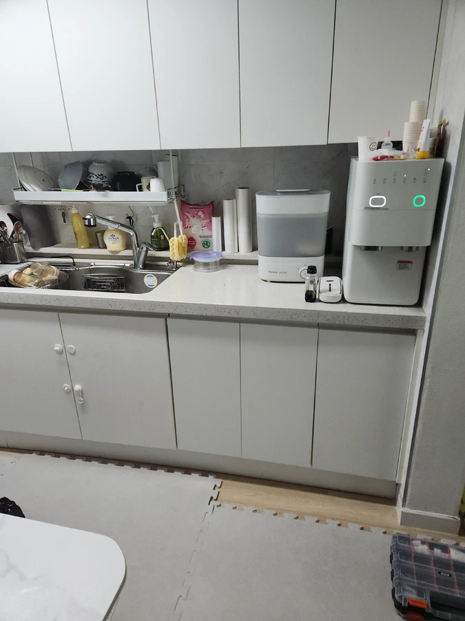 싱크대 하부장 내부의 급수 밸브와 배관 상태를 점검하는 기사님